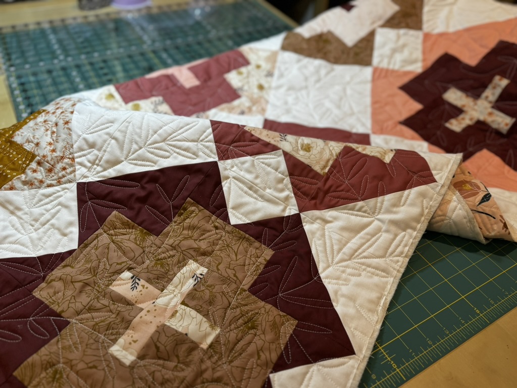 A modern baby quilt with maroon, cream, and burnt umber colors