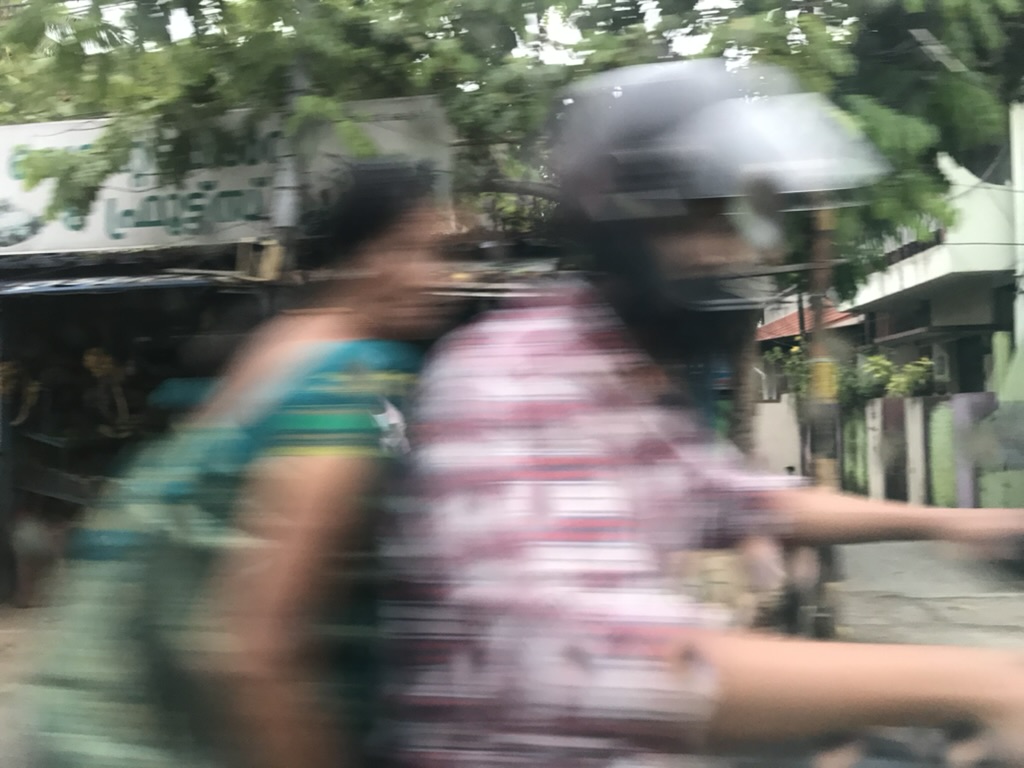 A man and woman whizz by in a blur on a motorbike.